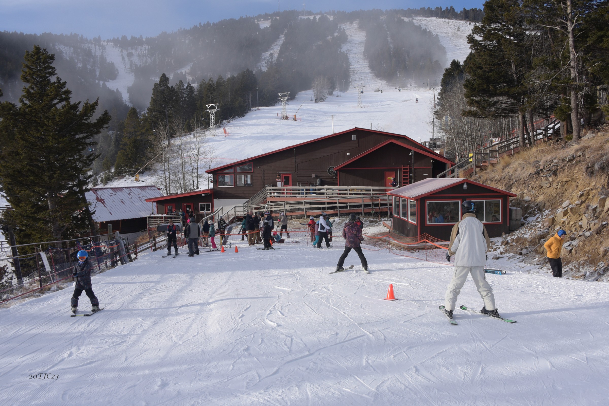 Skiers beside the lodge and snowy slopes at Great Divide Ski Area